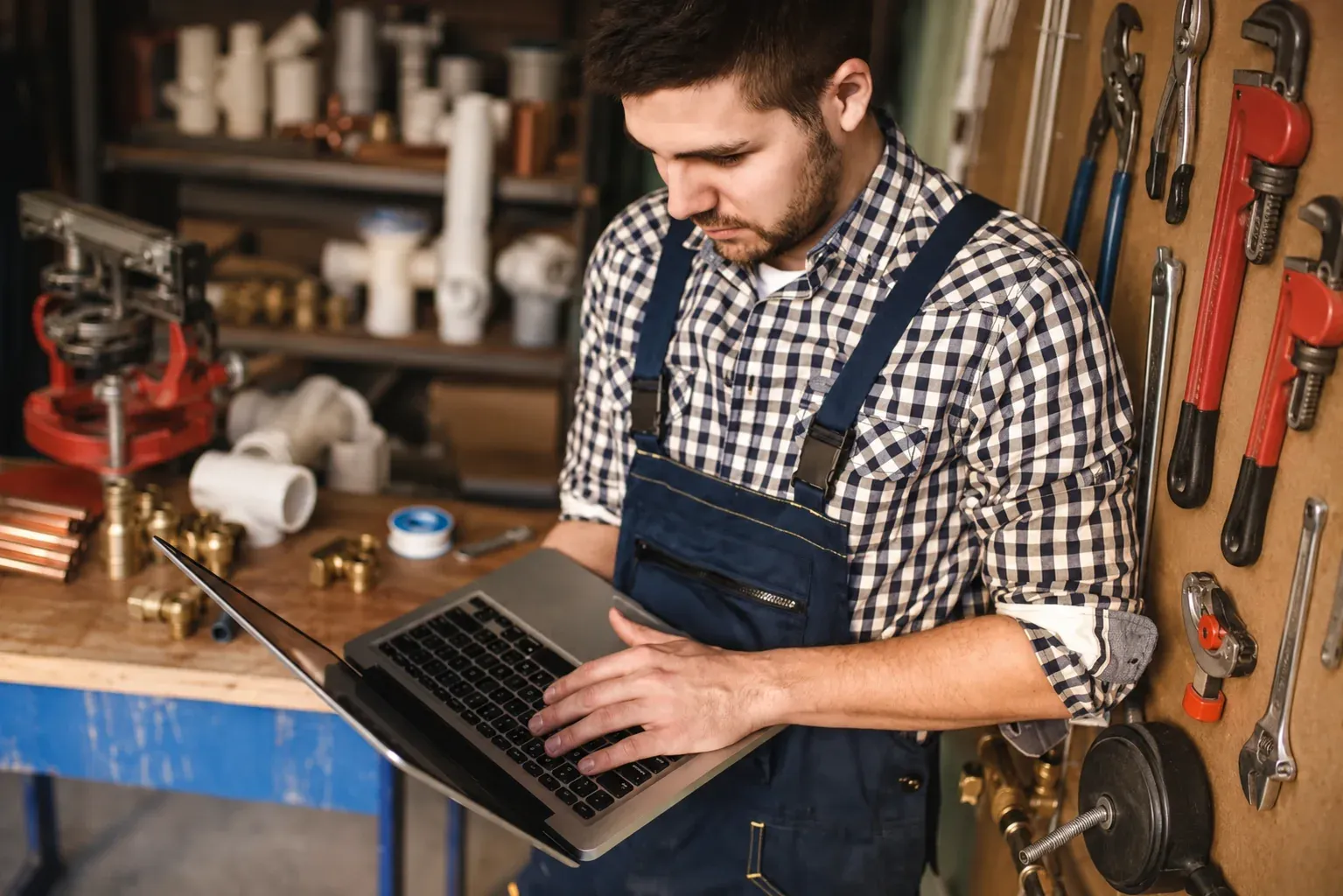 An HVAC technician in his workshop checking his business on a laptop